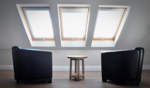 two chairs and a table in a room with three windows at Newport Links Golf Club , Pembrokeshire in Newport