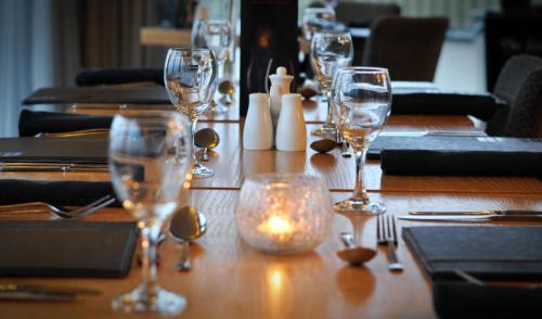 a wooden table with wine glasses and a candle on it at Newport Links Golf Club , Pembrokeshire in Newport Pembrokeshire