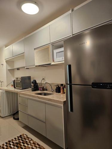Una cocina con refrigerador y gabinetes de acero inoxidable. en Apartamento um quarto Ilha Pura, Rio Centro, próx Parque Olímpico, en Río de Janeiro