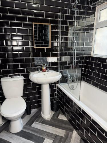 a black tiled bathroom with a toilet and a sink at Hampton Blues 3BR Entire Home in Stockton-on-Tees