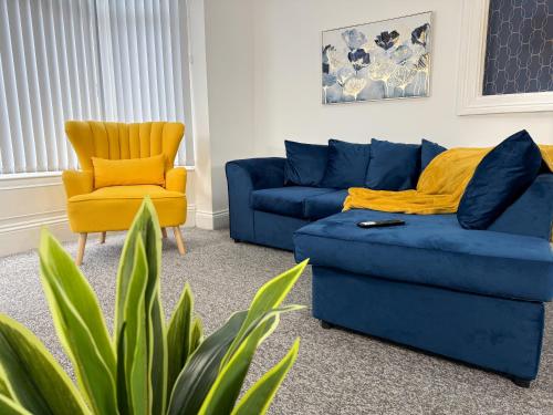 a living room with a blue couch and a yellow chair at Hampton Blues 3BR Entire Home in Stockton-on-Tees