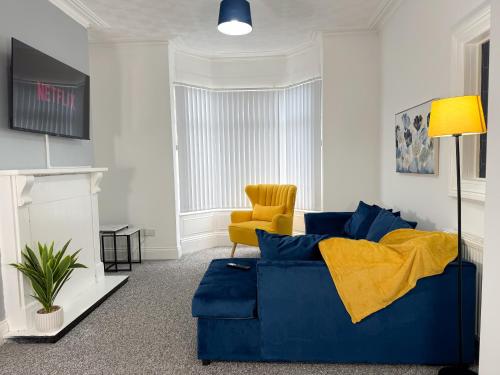 a living room with a blue couch and a yellow chair at Hampton Blues 3BR Entire Home in Stockton-on-Tees