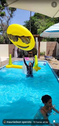 two people in a swimming pool playing with a frisbee at POUSADA NOSSO CANTO ALTER in Alter do Chao