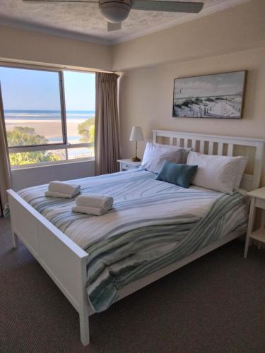 a bedroom with a large bed with a large window at Moorings Beach Resort in Caloundra