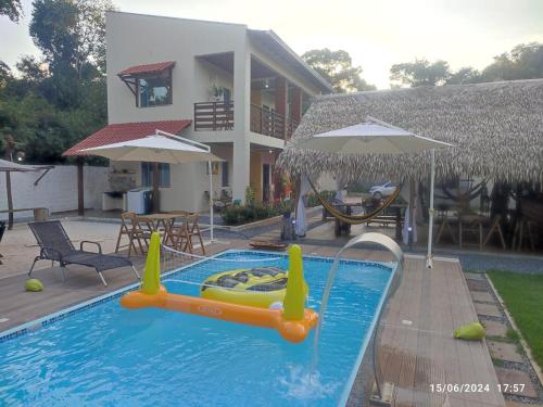 a swimming pool with an inflatable raft in front of a house at POUSADA NOSSO CANTO ALTER in Alter do Chao