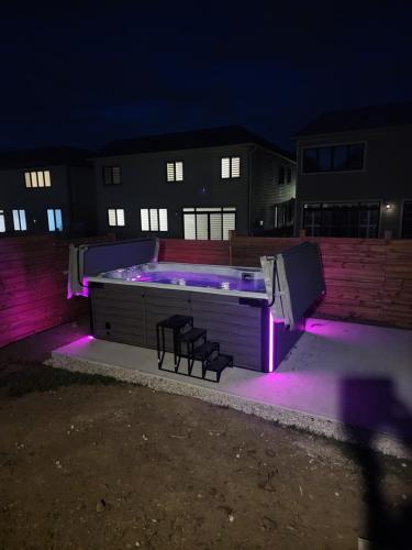 a swimming pool with two chairs and purple lights at PARADISE VILLa Bowmanville in Bowmanville