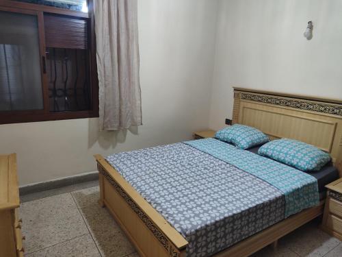 a bedroom with a bed with blue sheets and a window at Appartement immobilier à Fès in Ville Nouvelle