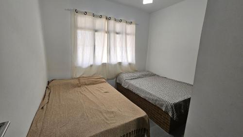 a small room with two beds and a window at Casa de praia in Buzios
