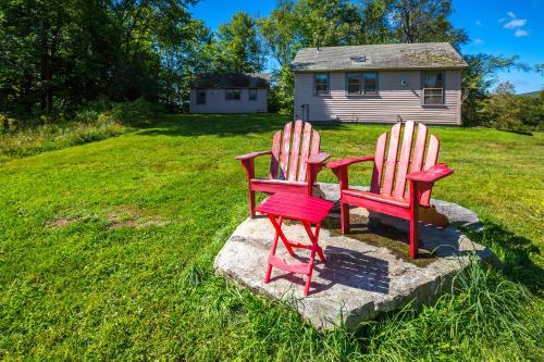 two red chairs sitting on a rock in a yard at 100 percent Private! Pool, Views, Skiing, Theatre! in Weston