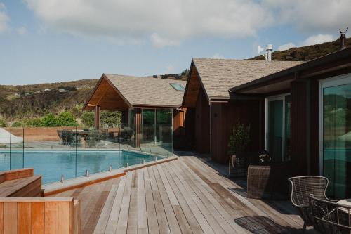 a house with a swimming pool and a wooden deck at Te Whaanga Retreat & Spa in Raglan