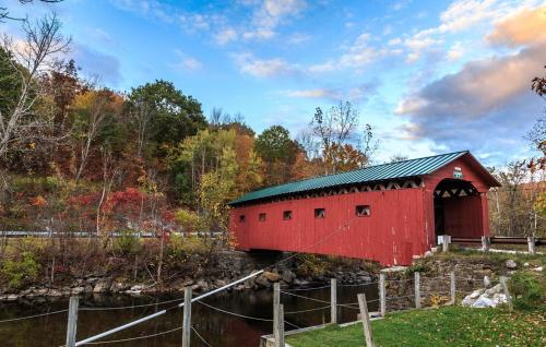 a red barn with a green roof next to a river at 100 percent Private! Pool, Views, Skiing, Theatre! in Weston