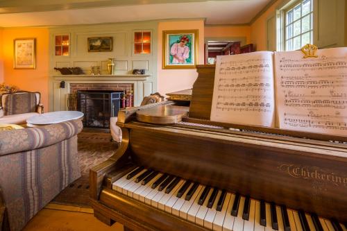 a piano in a living room with a fireplace at Fireplace, Ski-Okemo, Apple Trees, Piano, Amazing Views, Firepit, Priory, Pool, Fields, Theatre! in Weston