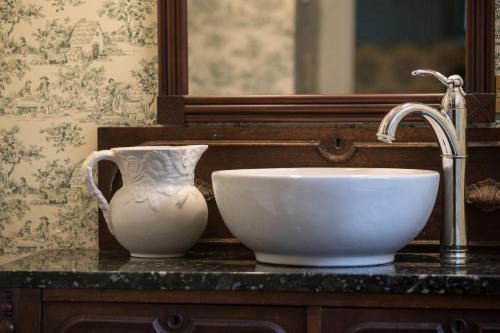 a sink and a vase on a counter next to a mirror at Fireplace, Ski-Okemo, Apple Trees, Piano, Amazing Views, Firepit, Priory, Pool, Fields, Theatre! in Weston