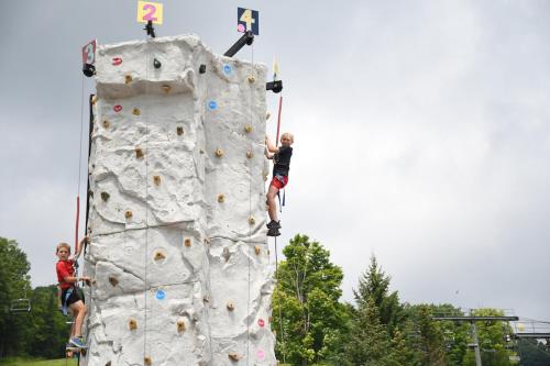 two boys are climbing on a rock wall at Fireplace, Ski-Okemo, Apple Trees, Piano, Amazing Views, Firepit, Priory, Pool, Fields, Theatre! in Weston