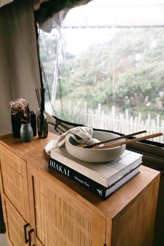 a table with books and a bowl on top of a window at Te Whaanga Retreat & Spa in Raglan