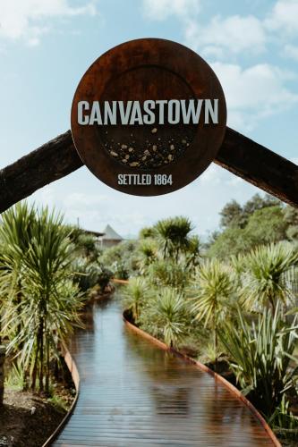 a sign that reads campariosswana is hanging over a river at Te Whaanga Retreat & Spa in Raglan