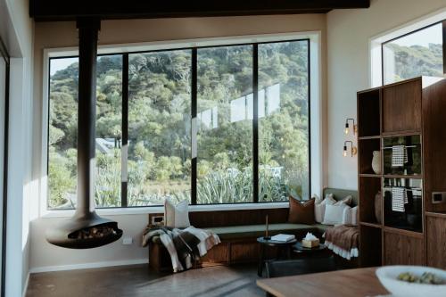 a living room with a large window with a fireplace at Te Whaanga Retreat & Spa in Raglan