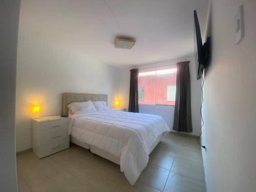 ein Schlafzimmer mit einem weißen Bett und einem Fenster in der Unterkunft Cajamarca Verde y bonita BI in Cajamarca