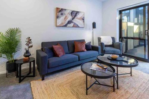 a living room with a blue couch and two tables at 4 Minutes walk to Riverside Market!4bed 4 bath in Christchurch