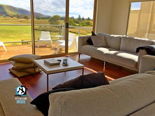 a living room with couches and a table with a view at Contemporary Golf Course Frontage 3BR in Normanville