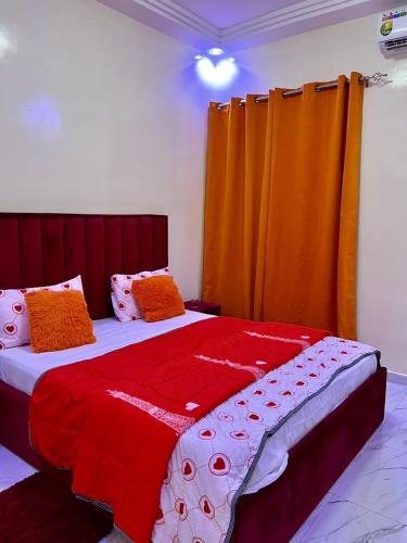 Un dormitorio con una cama grande con cortinas naranjas. en studio meuble, en Ngor