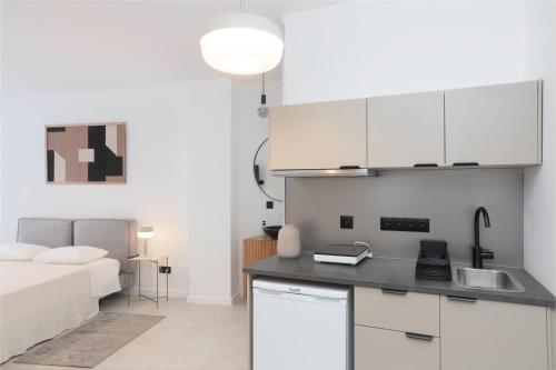 een keuken met witte kasten en een bed in een kamer bij Oporto Charming Studio Gaia in Vila Nova de Gaia