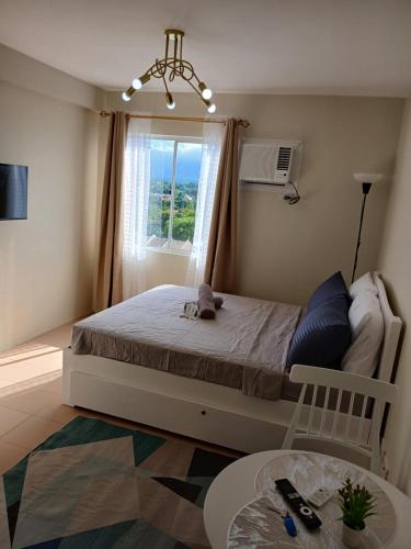 a bedroom with a bed with a window and a table at Mountain Views Studio Two Dumaguete in Dumaguete
