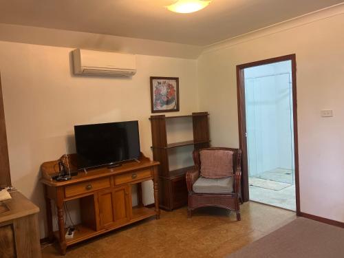 a room with a television and a desk with a chair at Potters Cottage in Bellingen