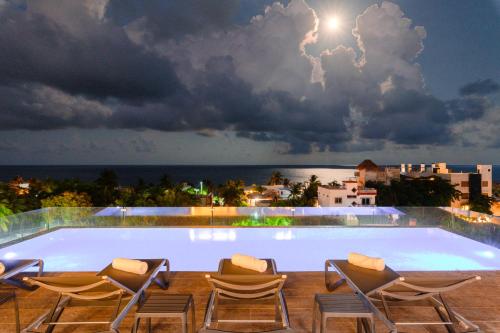a pool with chairs and a view of the ocean at Areia Boutique Hotel - Puerto Morelos in Puerto Morelos