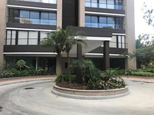 a building with palm trees in front of it at Class suites nirvana in El Poblado