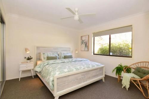 a white bedroom with a bed and a window at Collingwood Lodge by Experience Jervis Bay in Vincentia