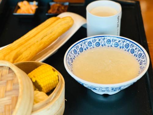 Ein Tisch mit einer Schüssel Suppe und einem Korb Mais in der Unterkunft Hilton Yantai Golden Coast in Yantai