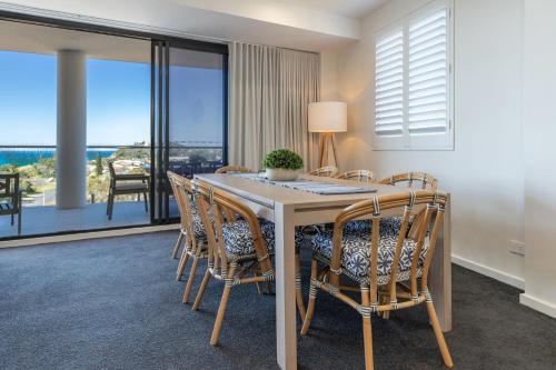 a dining room with a table and chairs with a view at Cove 701 in Forster