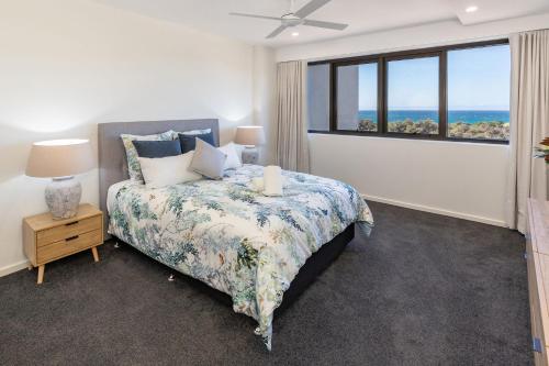 a bedroom with a bed with a view of the ocean at Cove 701 in Forster