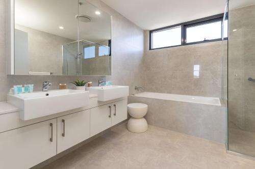 a bathroom with two sinks and a tub and a shower at Cove 701 in Forster