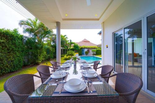 a dining table with plates and silverware on a patio at 4 Bedroom Private Pool Villa - MR51 in Hua Hin