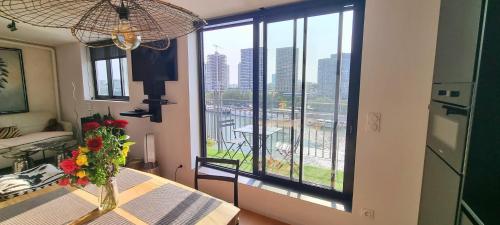 Cette chambre dispose d'une table avec un vase de fleurs et d'une fenêtre. dans l'établissement Appartement vue Tour Eiffel paris 16 Eme, à Paris