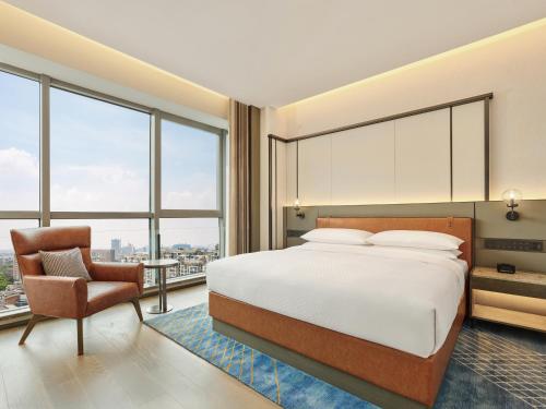 a bedroom with a bed and a chair and windows at Four Points by Sheraton Changzhou Economic Development Zone in Changzhou