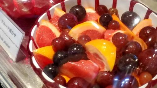 a bowl of fruit with grapes oranges and oranges at Dormy Inn Premium Namba Natural Hot Spring in Osaka