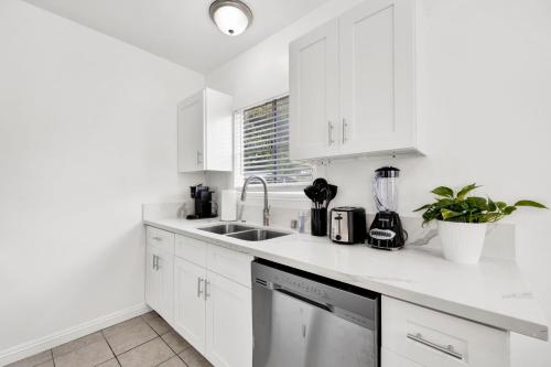 a white kitchen with white cabinets and a sink at Cozy Elegant Oasis With Parking in Los Angeles