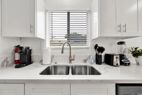 a white kitchen with a sink and a window at Cozy Elegant Oasis With Parking in Los Angeles
