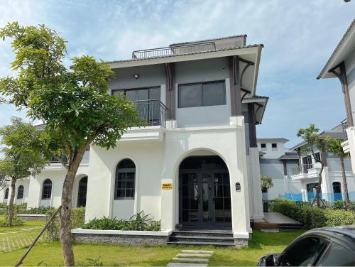 a large white house with a large door at Chuỗi Villa 3 Phòng ngủ Sonasea Vân Đồn - Đầy đủ tiện nghi - sân vườn BBQ - Sát bãi biển in Cái Rồng
