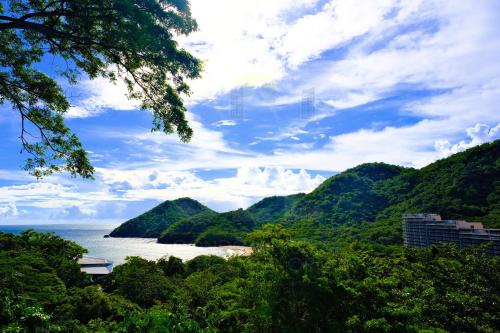 a view of a beach with mountains and the ocean at PICO DE LORO Pool Accessible CAROLA 3 Bedroom Units by SEE Condominiums in Cutad