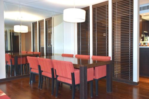 a dining room with a table and red chairs at Sathorn Vista, Bangkok - Marriott Executive Apartments in Bangkok