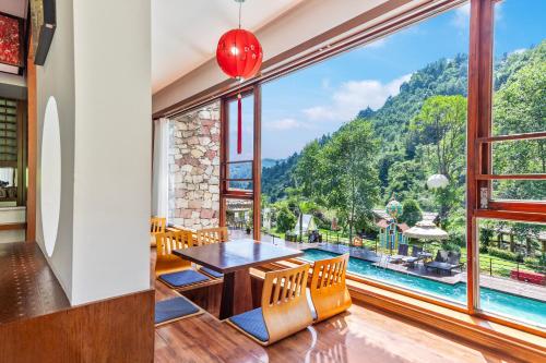 a dining room with a table and chairs and a large window at Pandora Vista Retreat in Zhangjiajie
