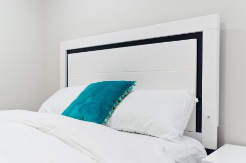 a white bed with a blue pillow on it at Executive Bliss Suites in Calgary