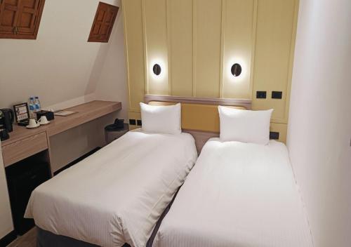 two beds in a small room with white sheets at 南兜漫旅 in Tainan