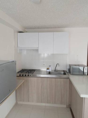 a kitchen with a sink and a microwave at Apartamento acogedor en Tocancipá in Bemposta