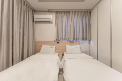 two beds in a small room with curtains at Staywell Hotel in Busan