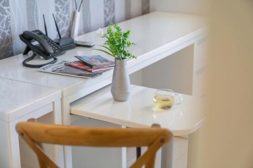 a white desk with a vase with a plant on it at Staywell Hotel in Busan